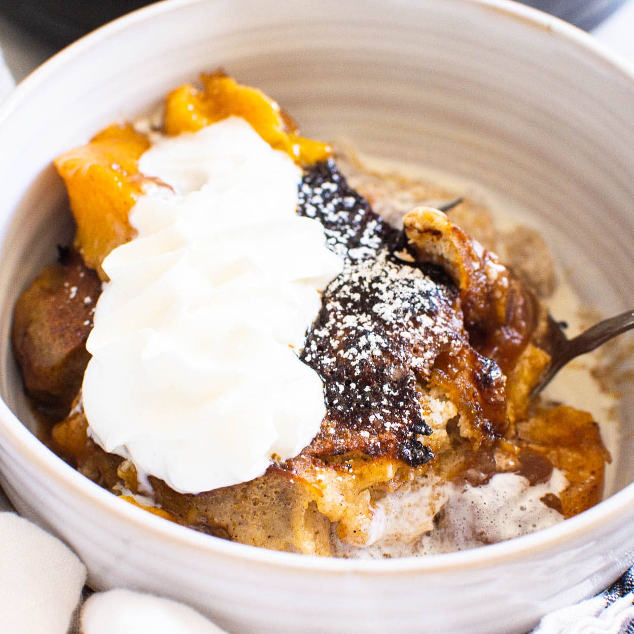 peach cobbler in bowl with whipped cream