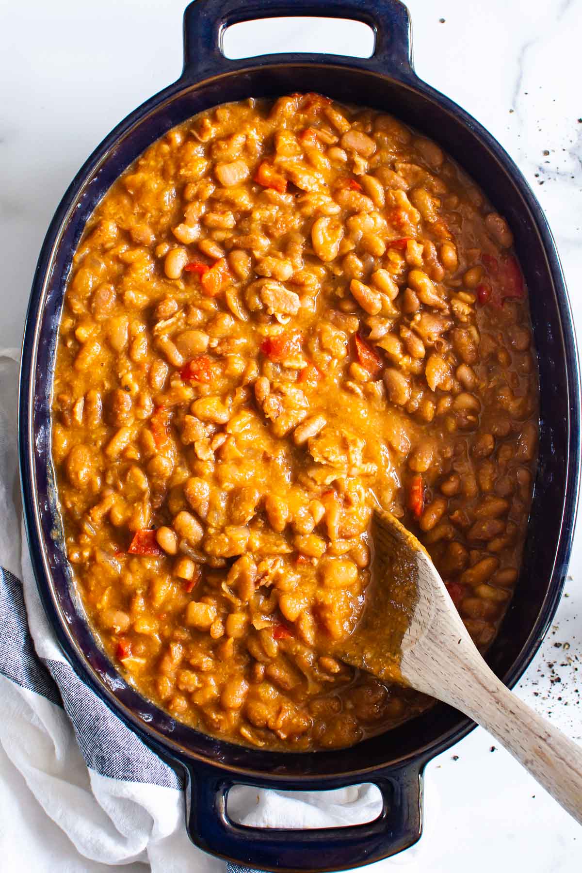 Instant pot baked beans in blue serving dish with wooden spoon.