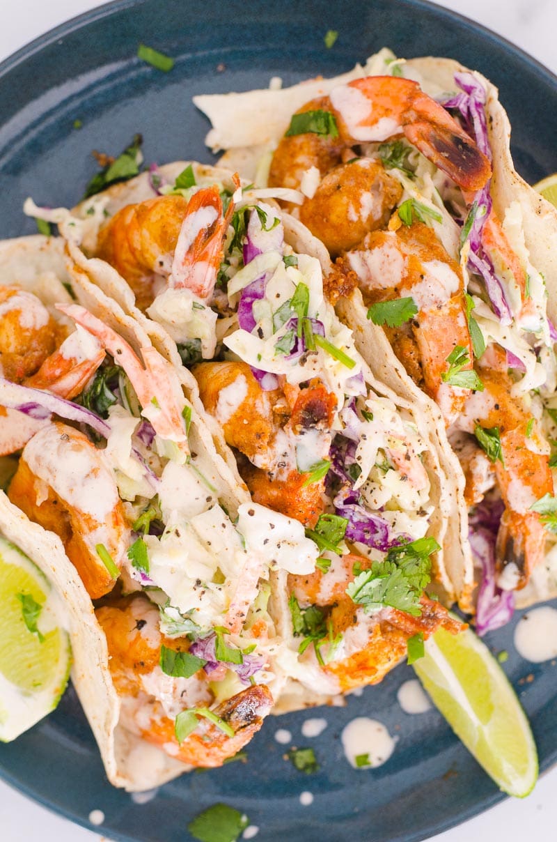 Three shrimp tacos served on a plate.