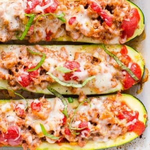 Ground turkey zucchini boats garnished with basil in a baking dish.