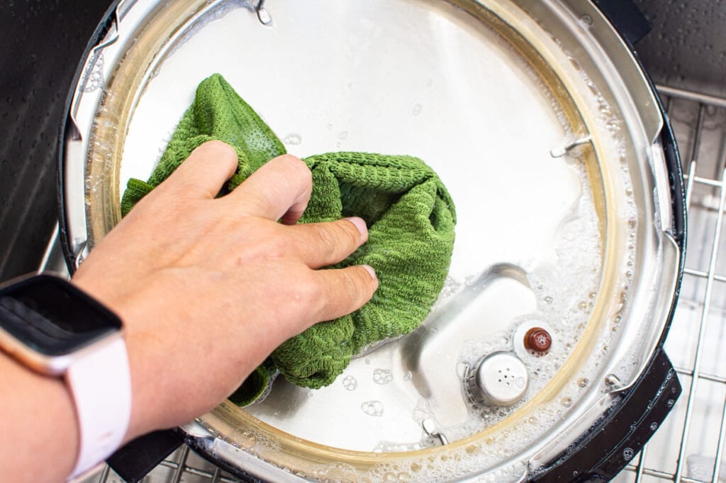 cleaning instant pot lid with soapy water inside