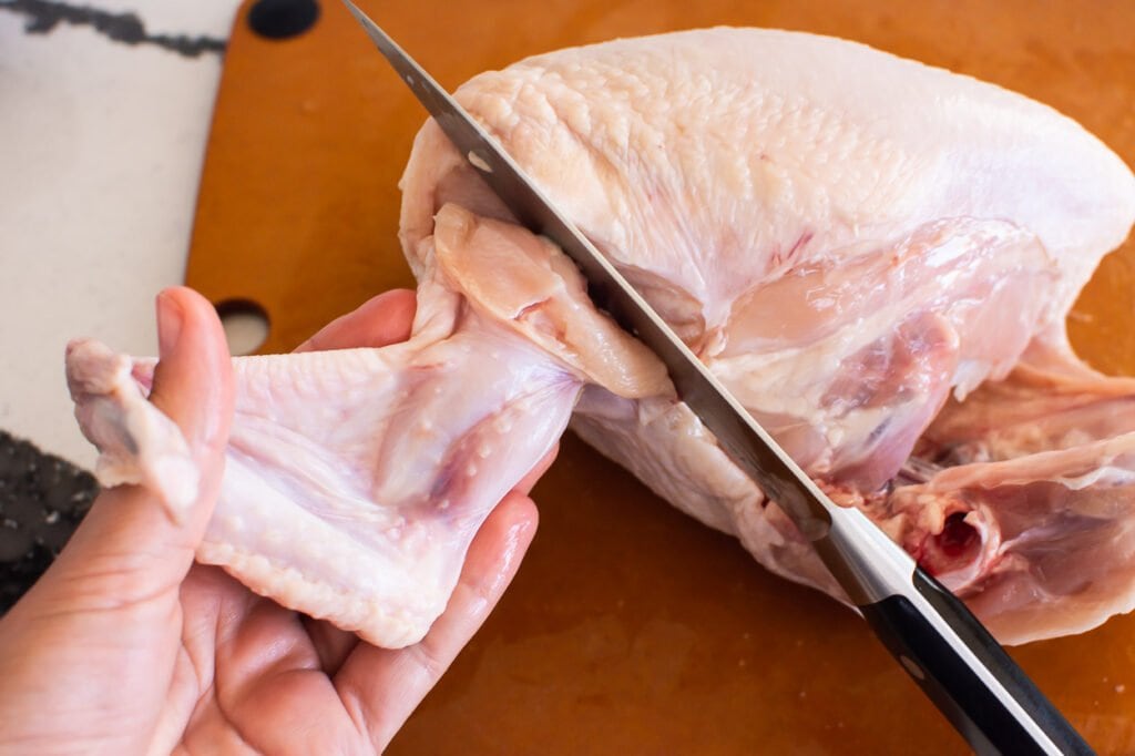 pulling wings away from cutting a whole chicken