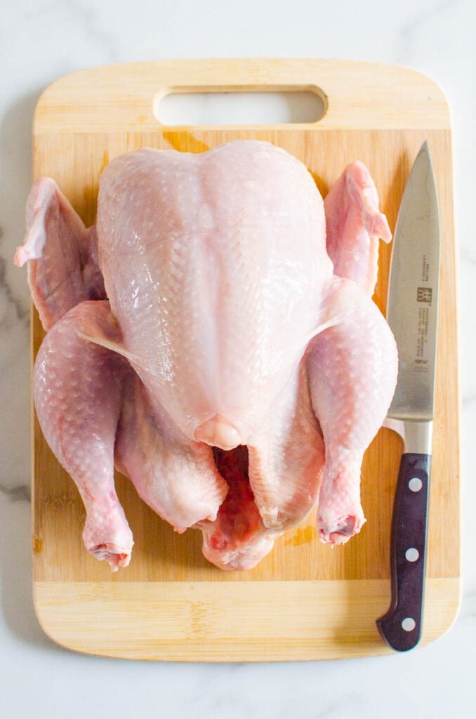  raw whole chicken on cutting board