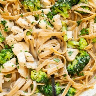 Healthy chicken alfredo with broccoli and wrapped around a fork.