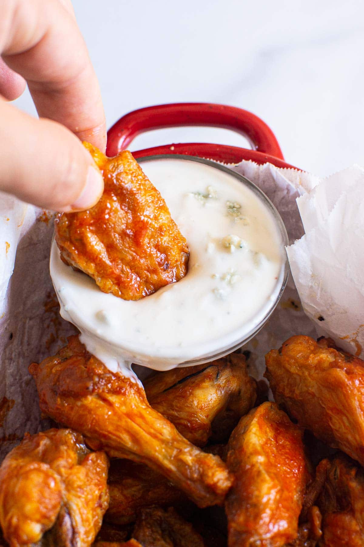 Dipping air fryer buffalo wing into blue cheese dip.