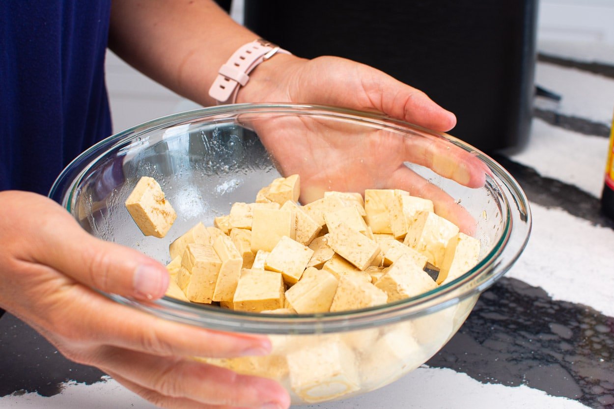 Tossing tofu cubes in glass bowl.