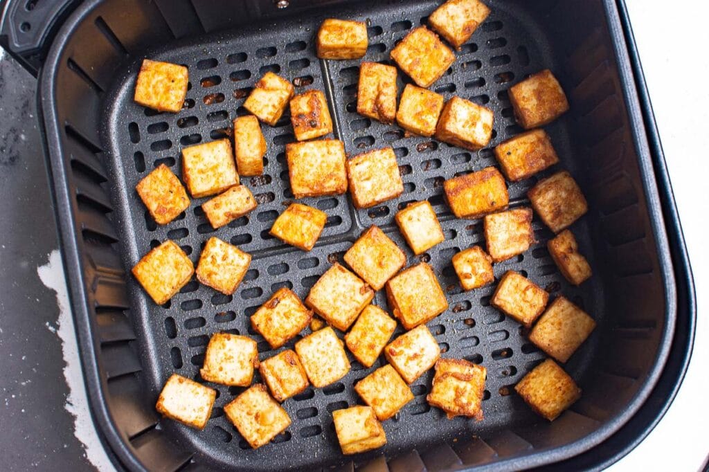 Air fried tofu in air fryer basket.