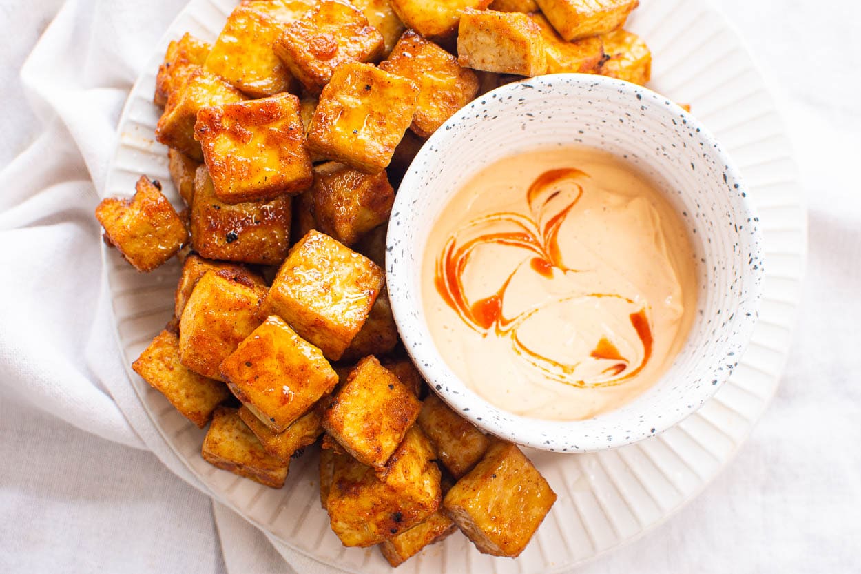 Air fryer tofu on plate with sauce on side in a bowl.