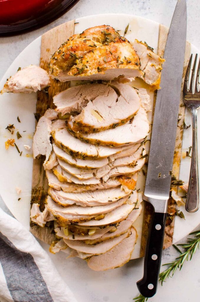 turkey breast roast sliced on a platter with knife and garnish