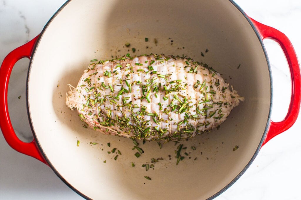 showing turkey breast in large dutch oven with herbs