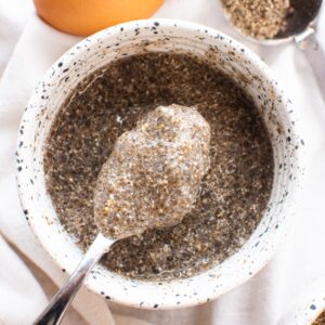 Chia egg on a spoon over white bowl.