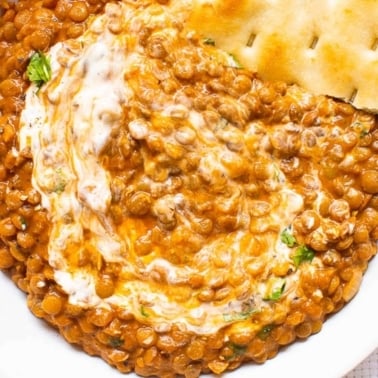 instant pot dal in a dish with flatbread and swirl of coconut milk