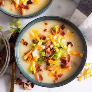 A bowl of Instant Pot potato soup garnished with bacon, cheese and green onions.