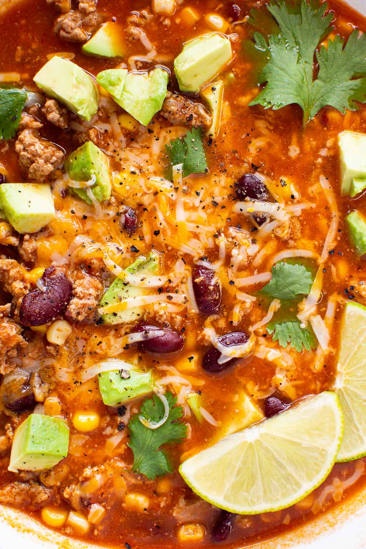 Closeup of turkey taco soup garnished with avocado, cheese and cilantro.