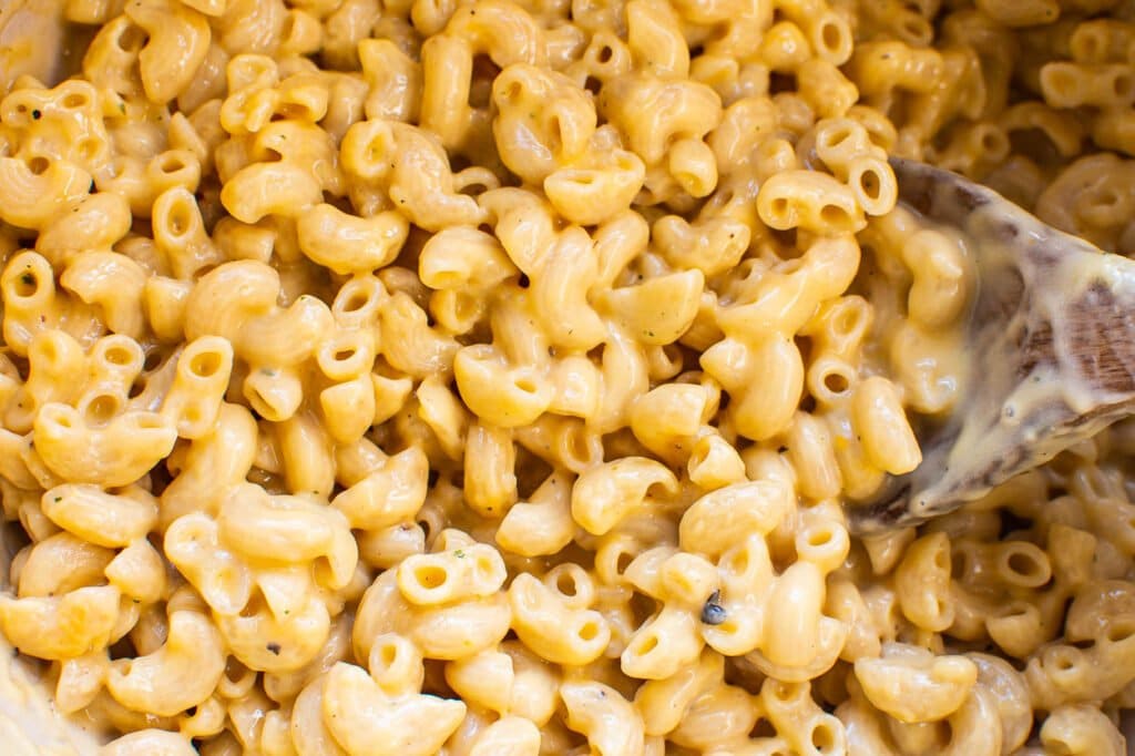 macaroni and cheese sprinkled with seasoning with a spoon dipped into it for serving