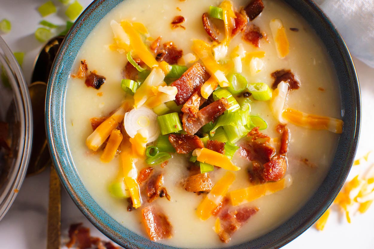 Instant Pot potato soup with green onions, chopped bacon, and cheese.