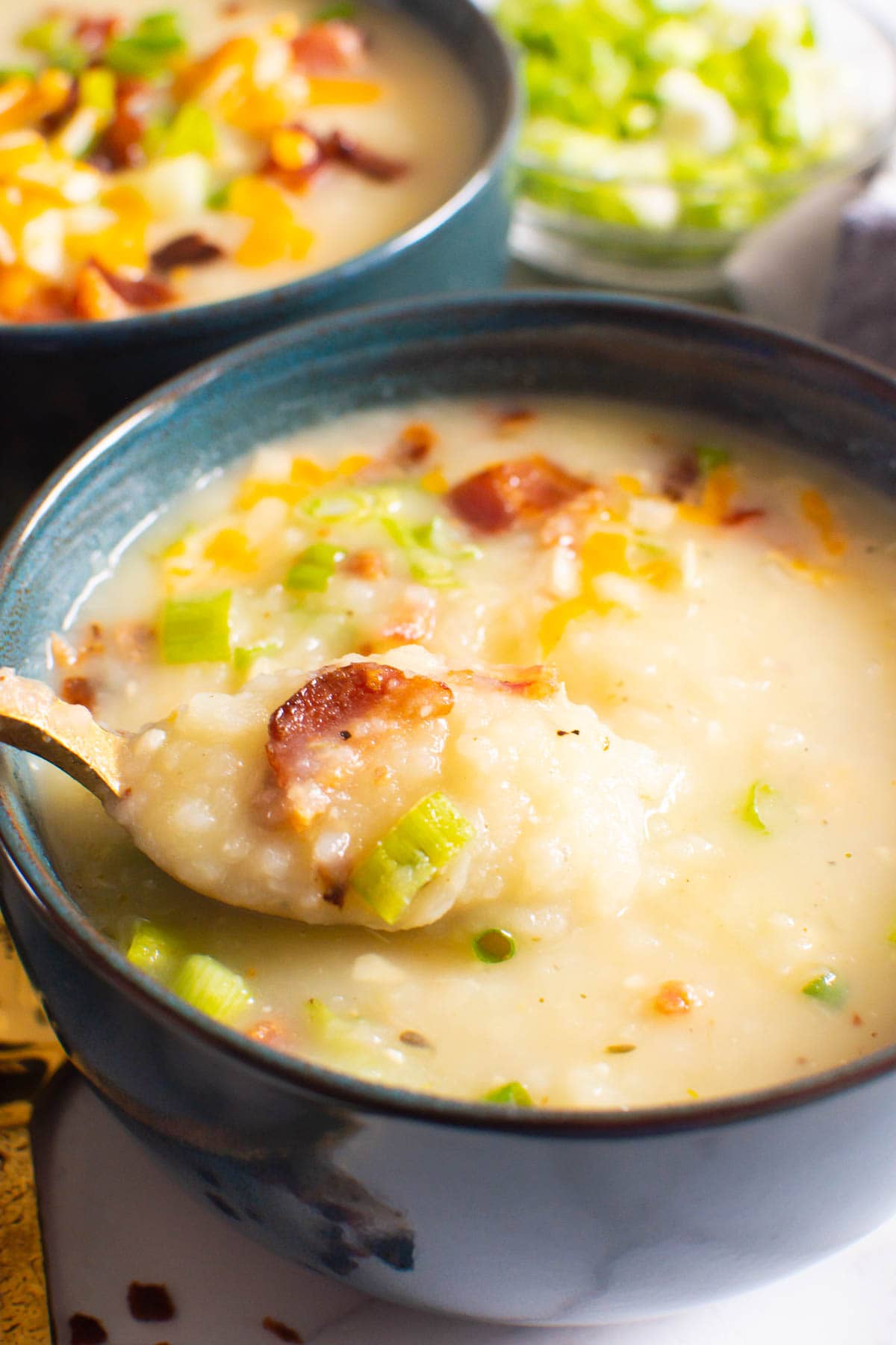 Closeup of Instant Pot potato soup on a spoon with bacon and green onion.