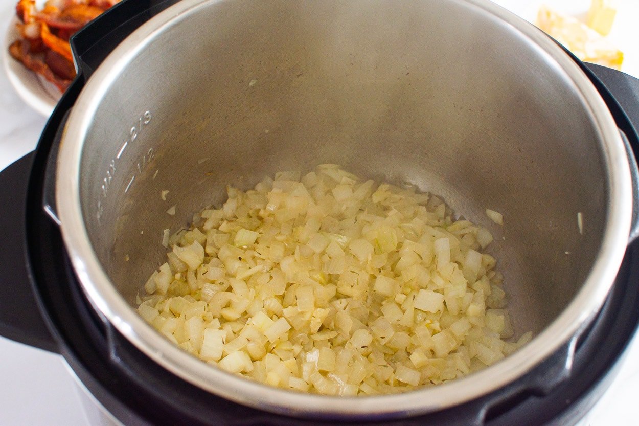 Chopped onion, garlic, and thyme sauteing in butter inside Instant Pot.