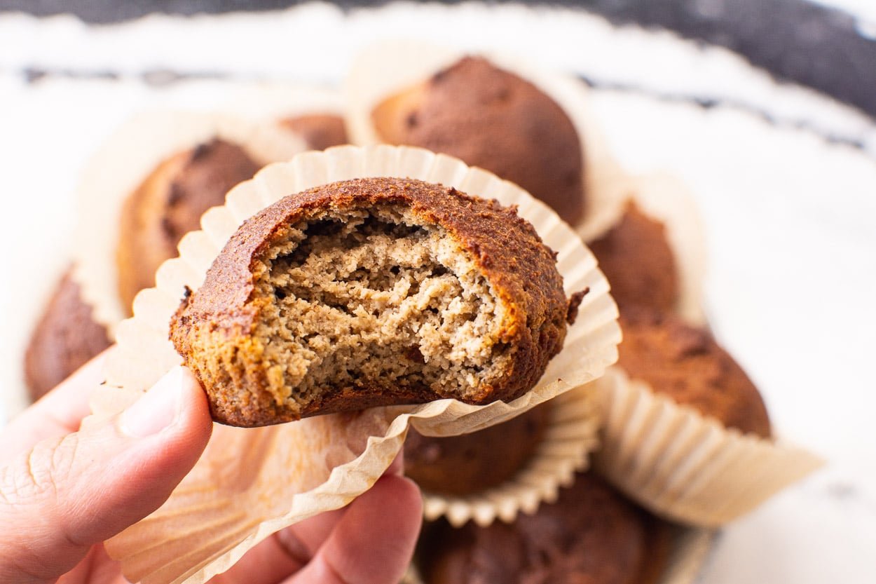 A hand holding almond flour banana muffin made with flax egg in parchment liner.