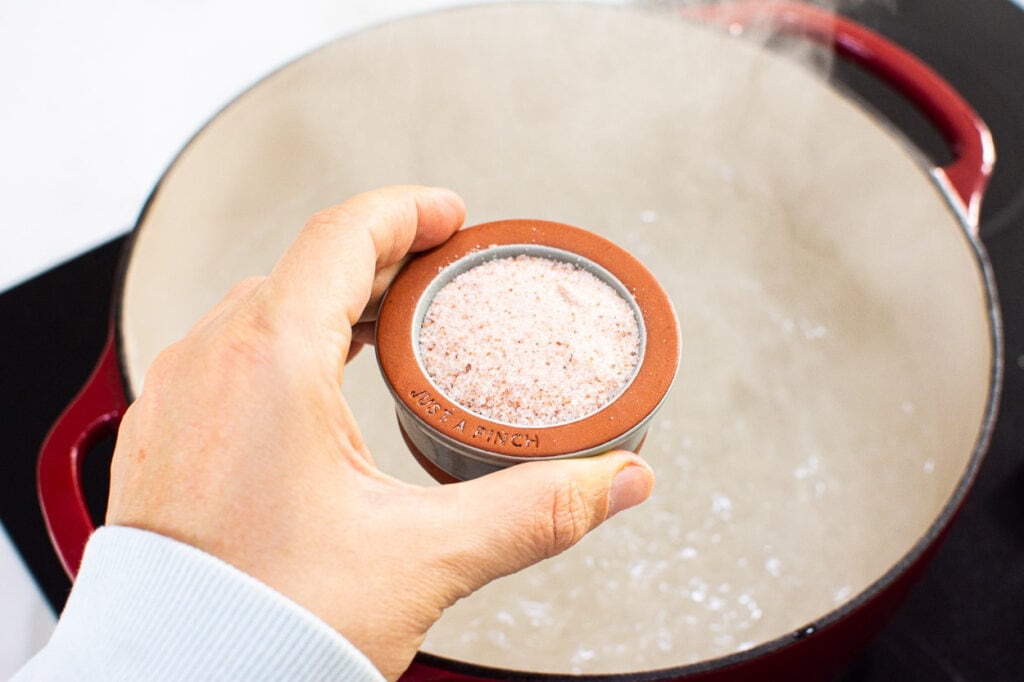 A small bowl of salt being held over boiling water.