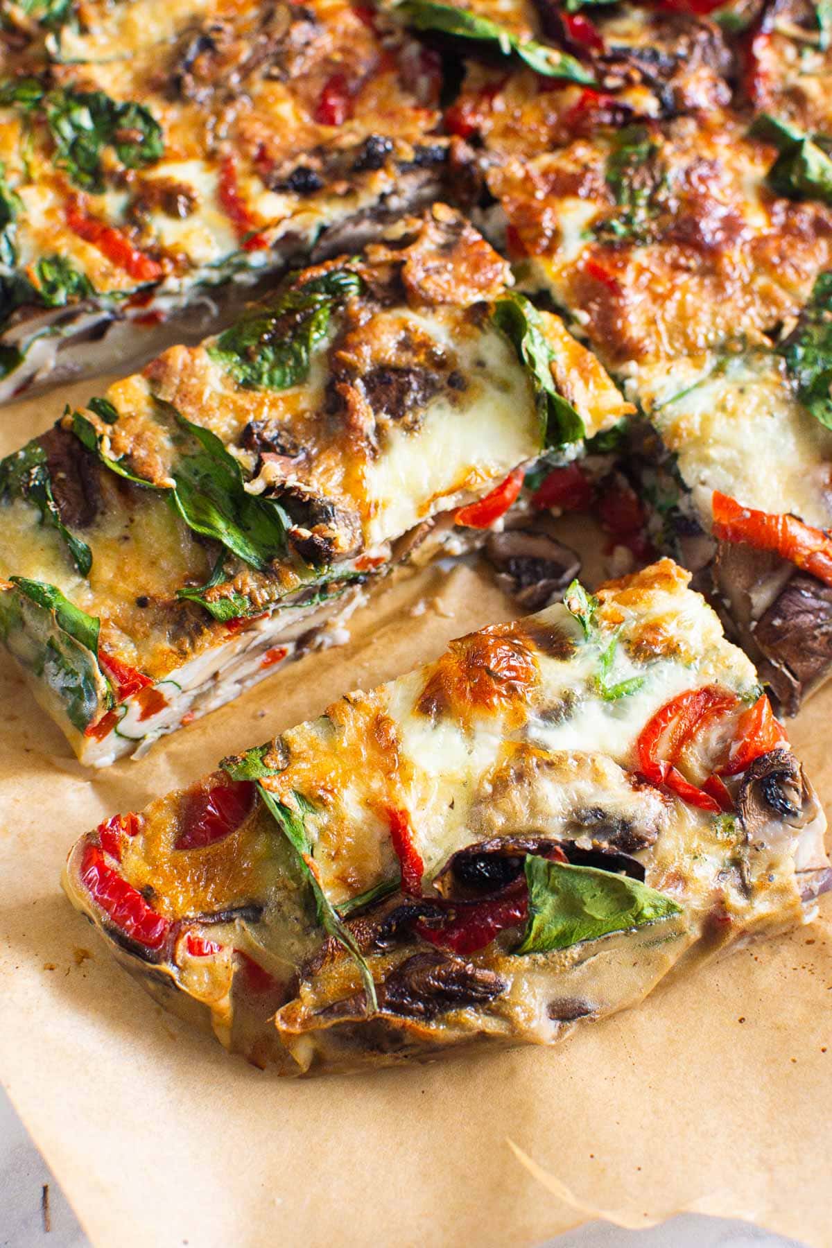 Air fryer breakfast casserole with mushrooms, spinach and peppers sliced on parchment paper.