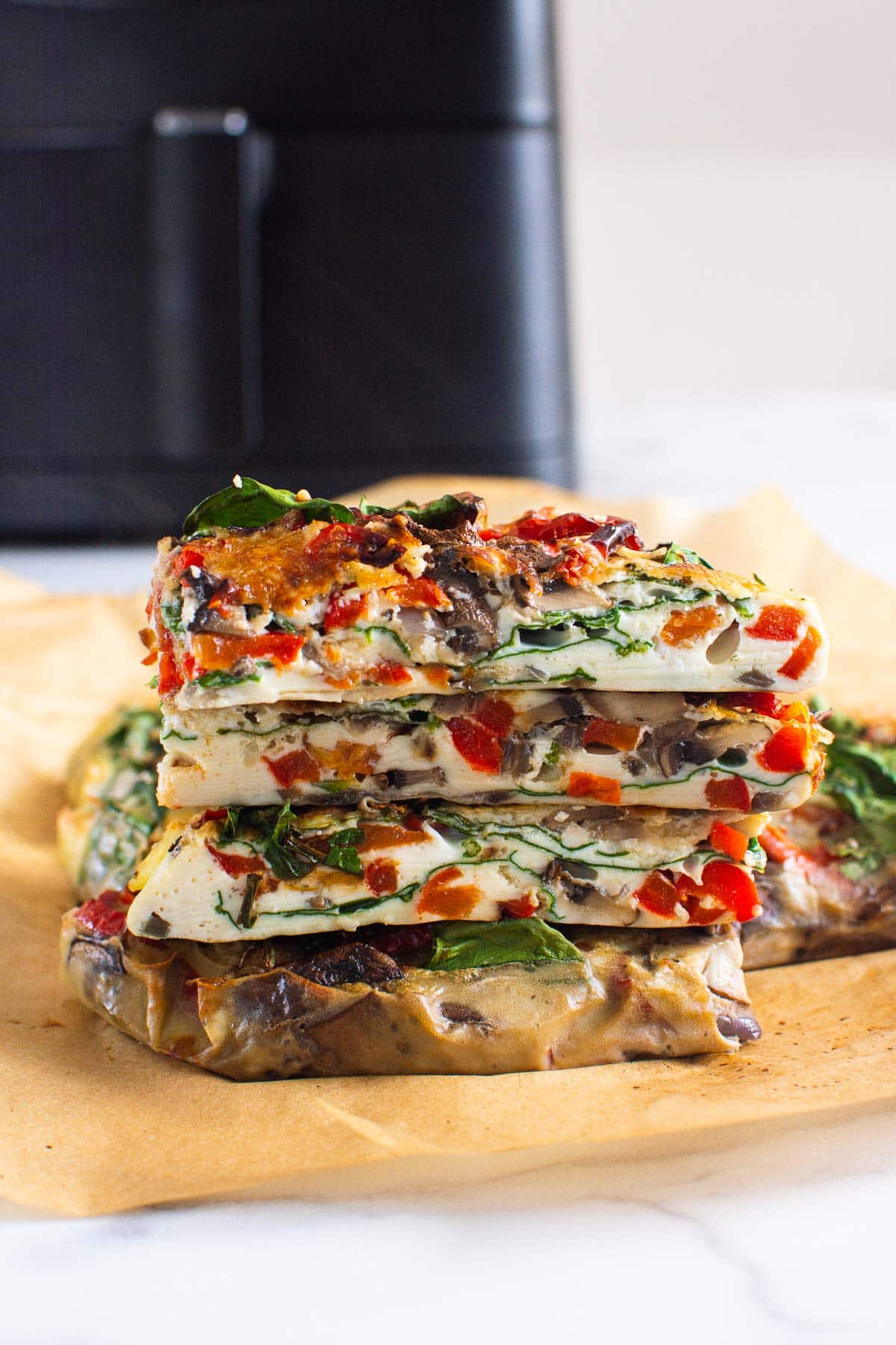 Stacked slices of breakfast casserole with spinach, pepper and mushrooms.