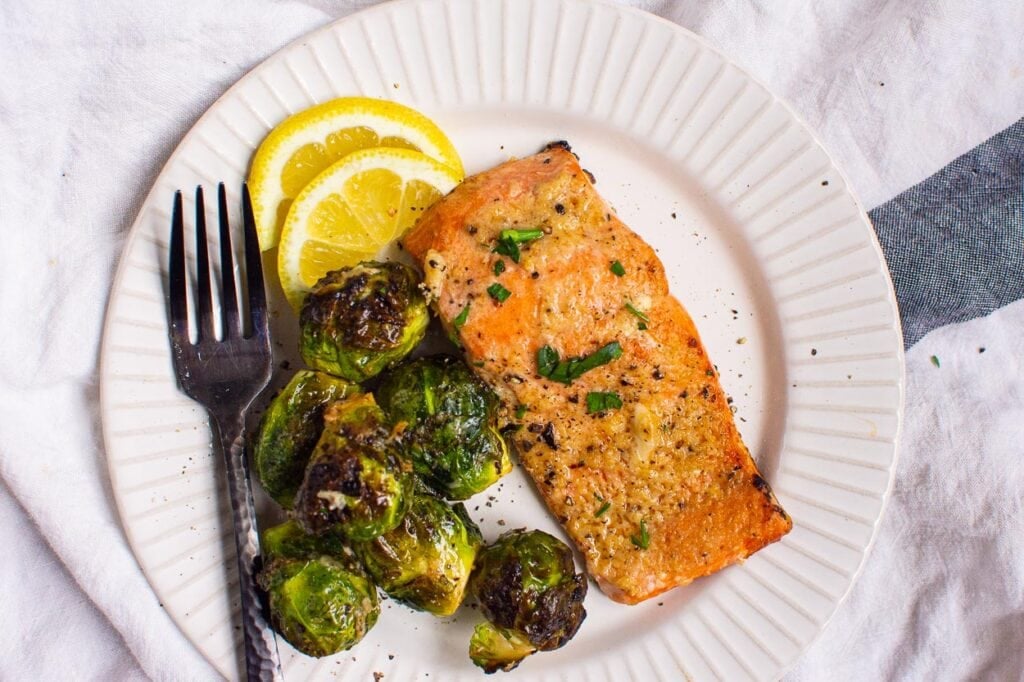 plated air fryer salmon with brussels sprouts and lemon wedges