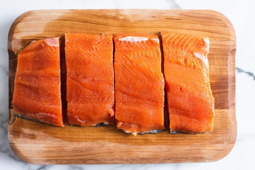salmon cut into four pieces on a cutting board