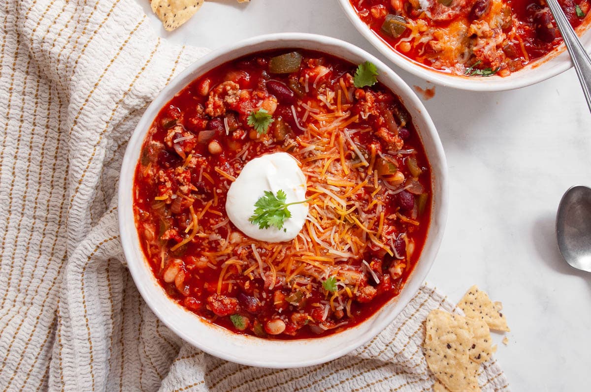 Turkey chili in a bowl with sour cream, cheese and cilantro.