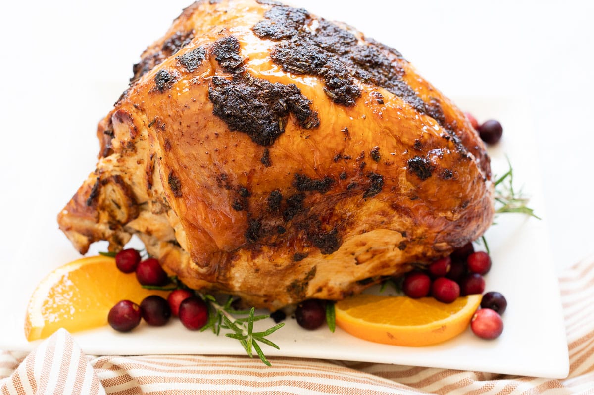 Roasted bone in turkey breast roast on white platter.