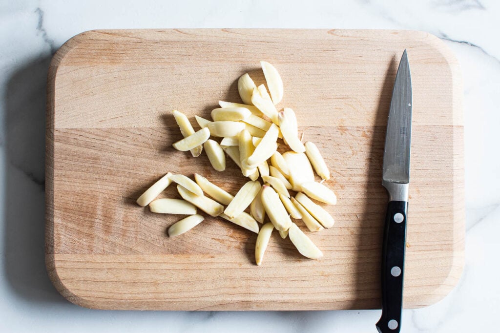 garlic slivers on a cutting board and knife