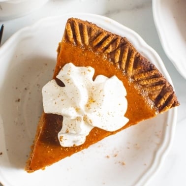 Healthy pumpkin pie with whipped cream on plate.