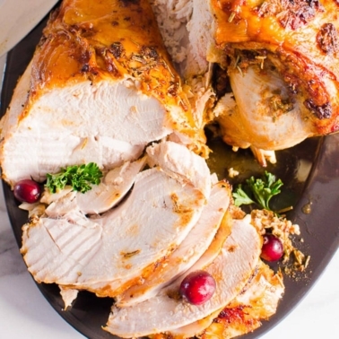 turkey breast sliced on a platter with garnish and cranberries