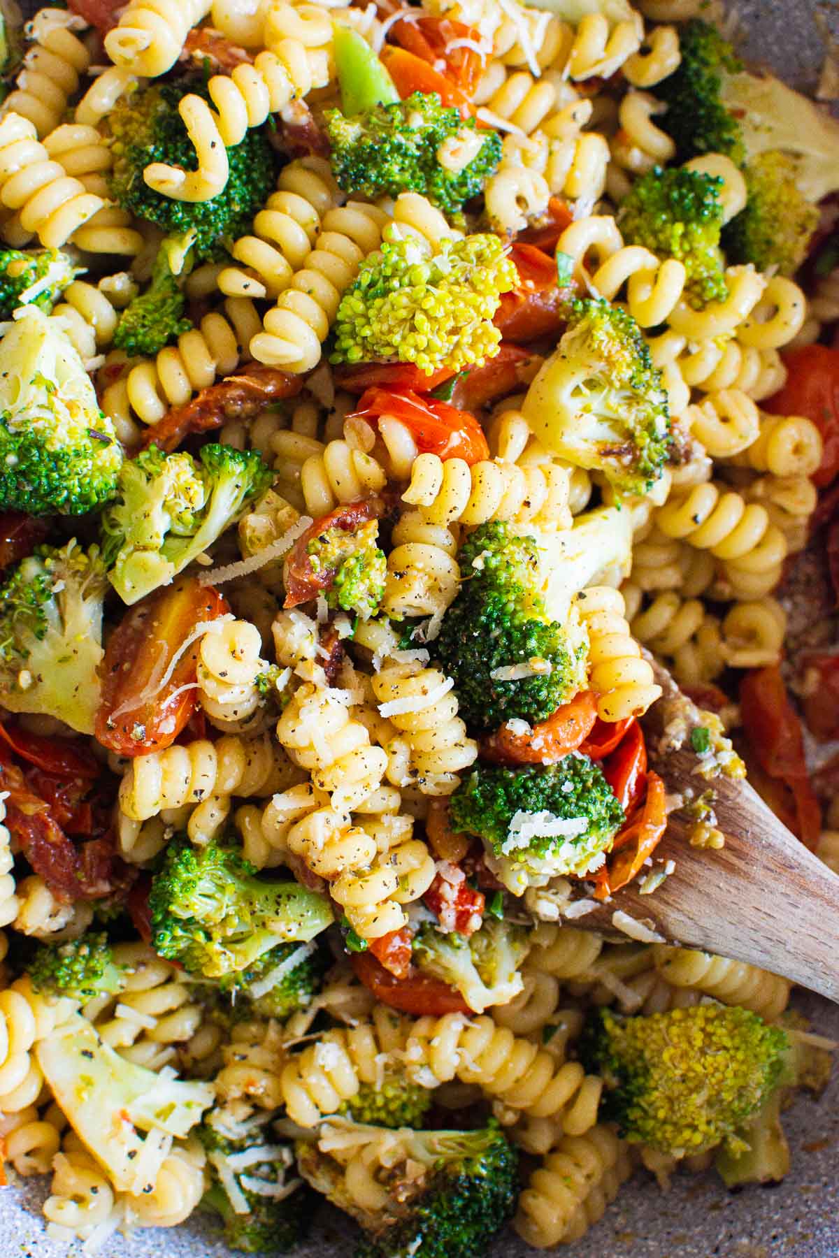 Healthy pasta with pesto and broccoli close up with a spoon dipped into it to show texture.