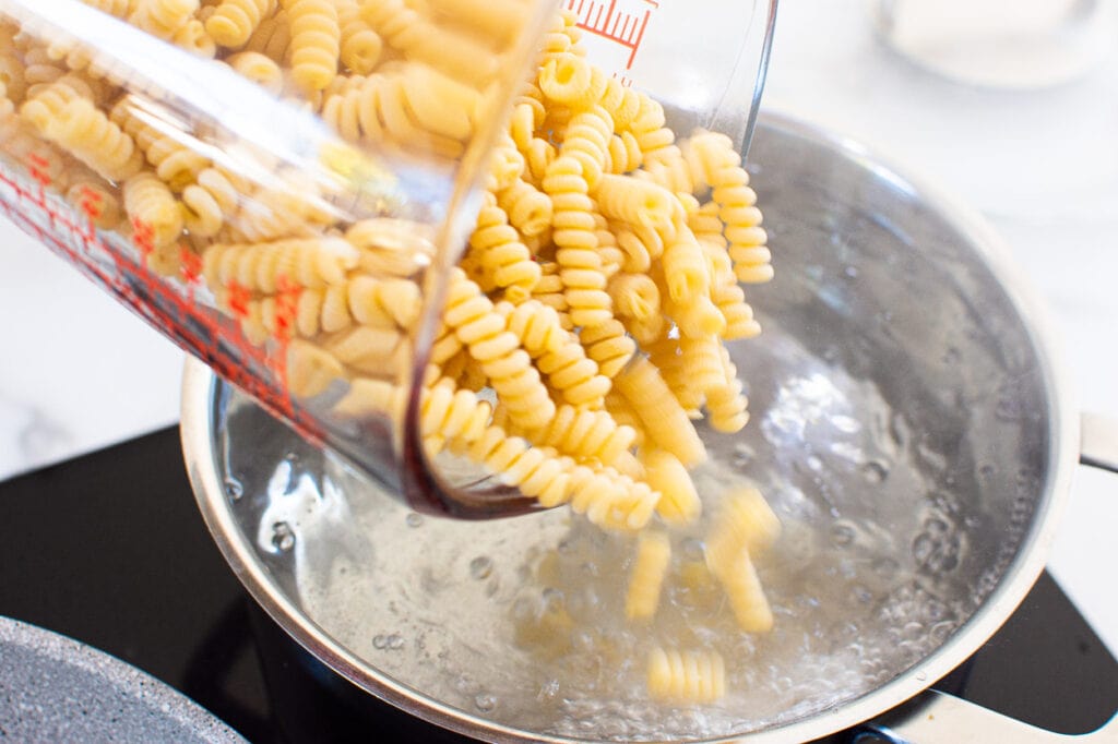 Pouring dry pasta into boiling water.