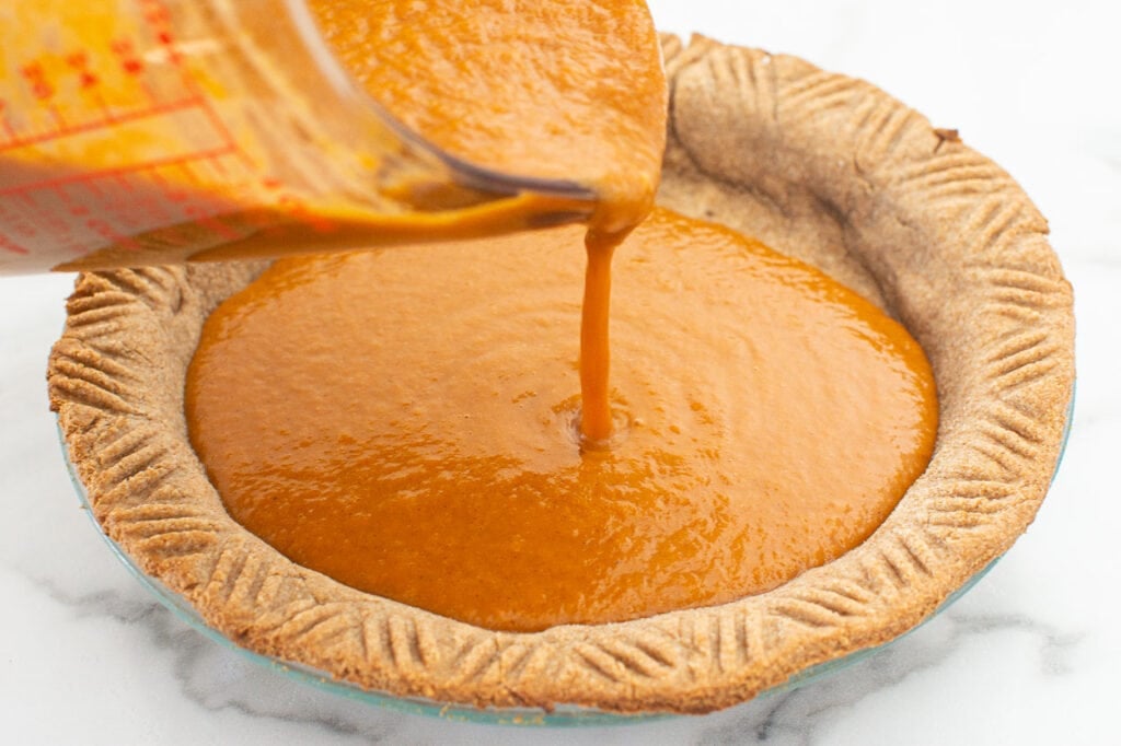 pouring pumpkin pie filling into pie crust and bake