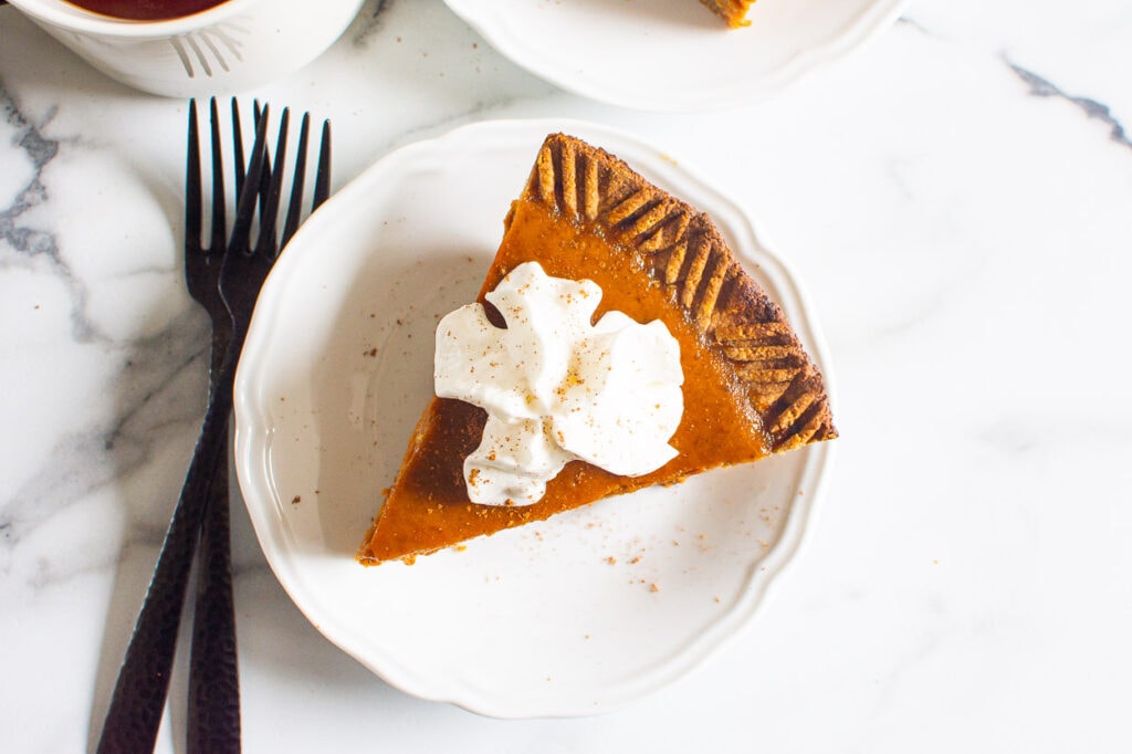 healthy pumpkin pie cut onto a plate with whip cream