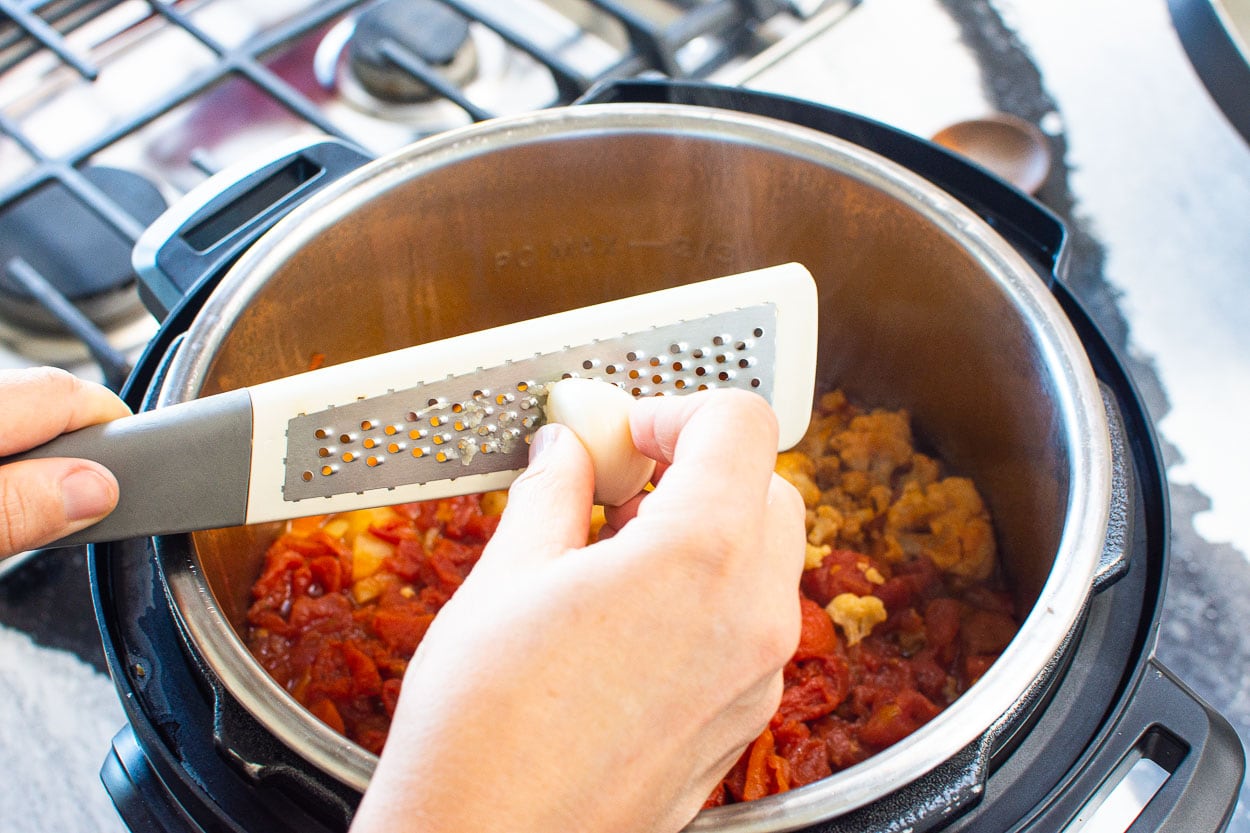 Grating garlic on top of Instant Pot vegetable soup.