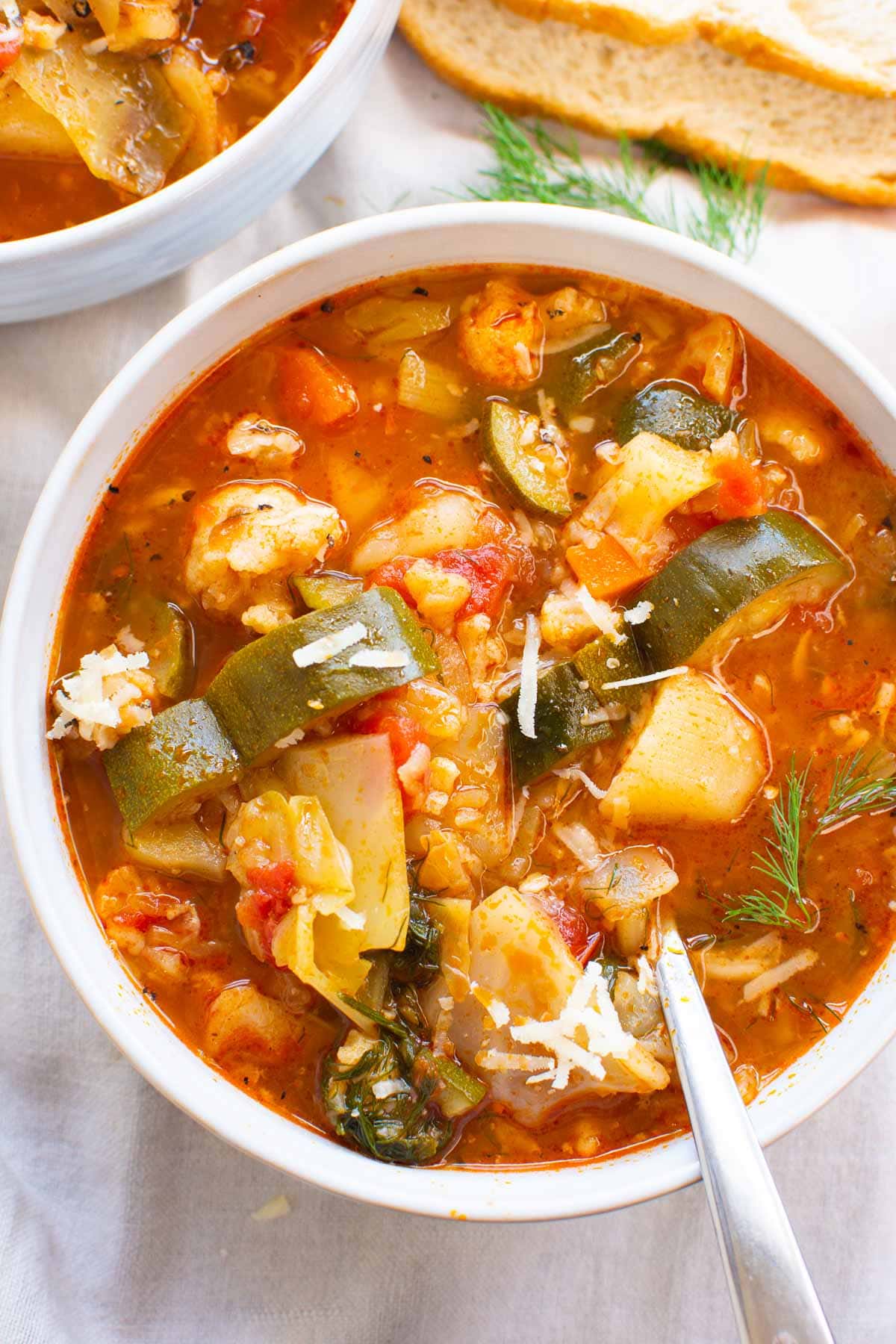 Two bowls of Instant Pot vegetable soup garnished with parmesan cheese. Bread for serving.