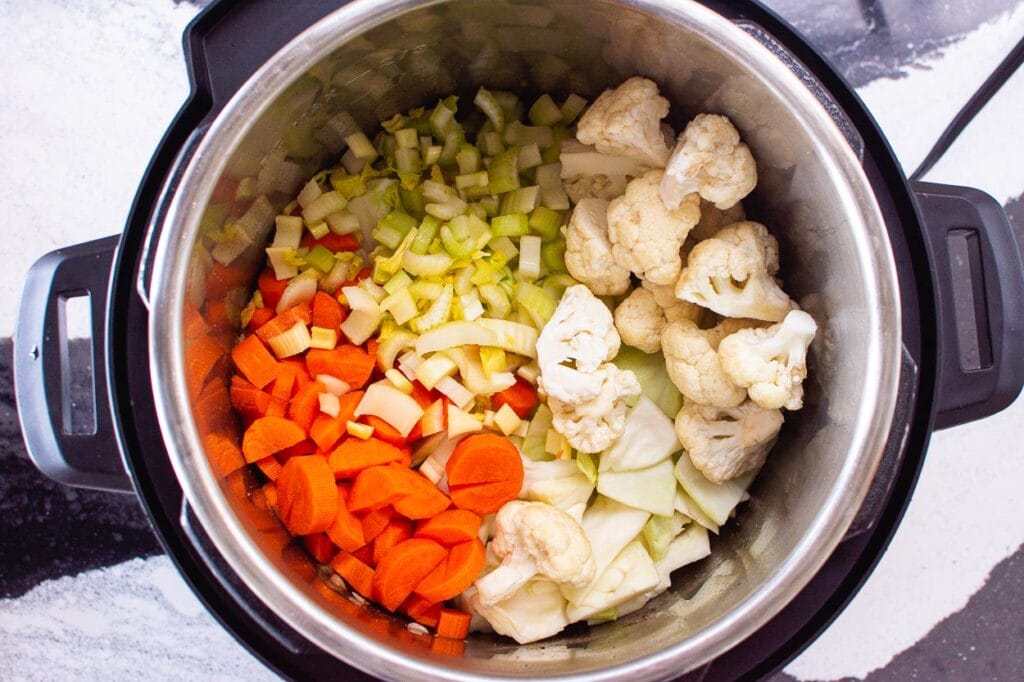adding vegetables to pressure cooker for soup