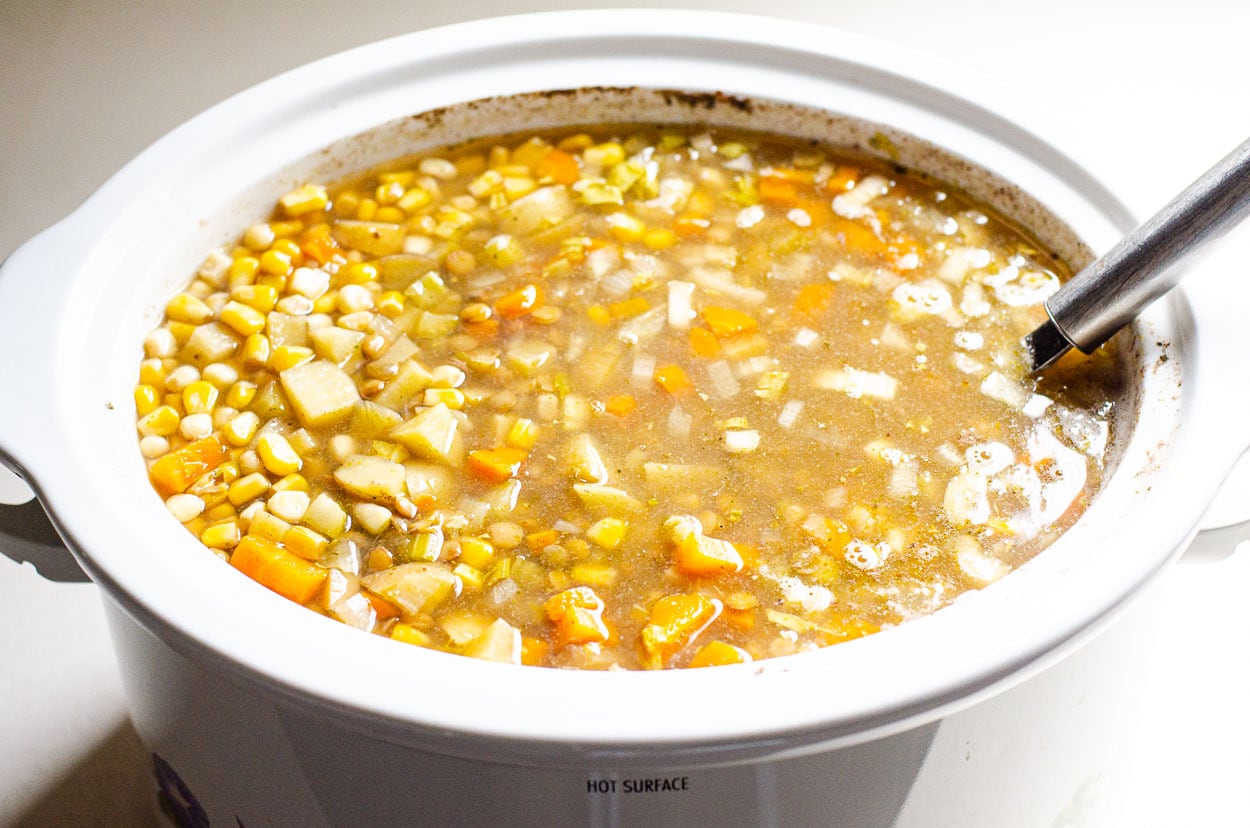 Crockpot lentil soup with serving ladle.