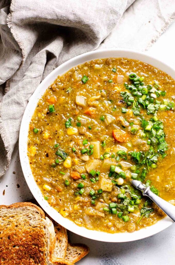 lentil soup made in crock pot in a bowl for serving with a gray linen and crusty brown bread