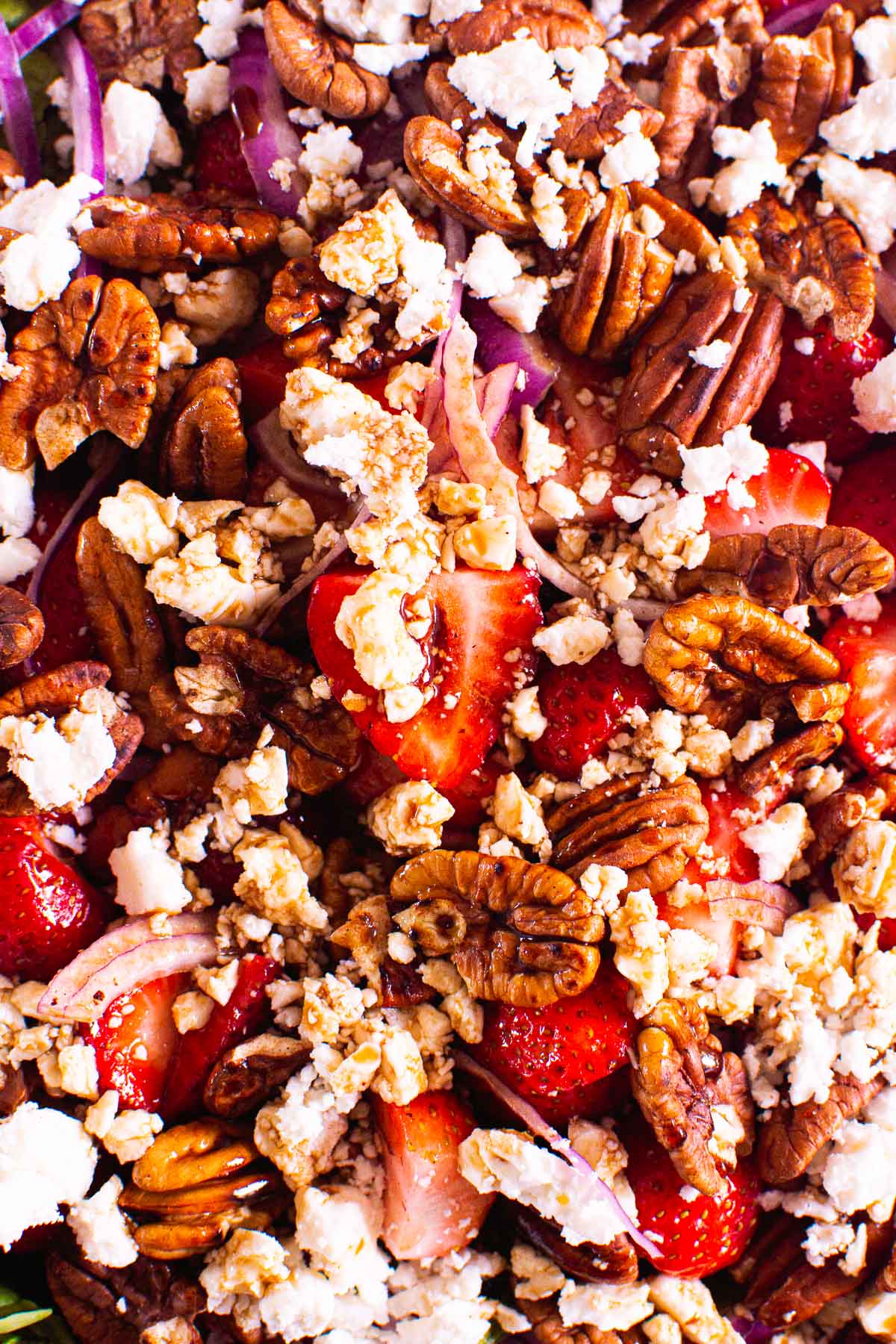 Close up pecans, strawberries, red onion and feta for strawberry spinach salad.