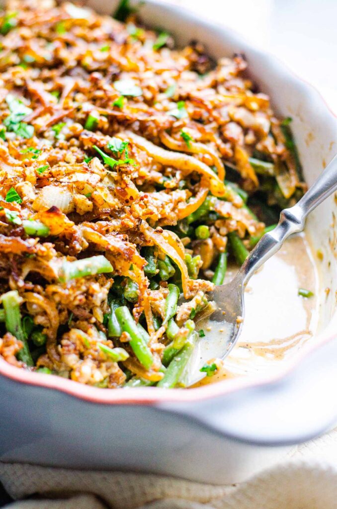 Healthy green bean casserole in serving dish with a spoon.