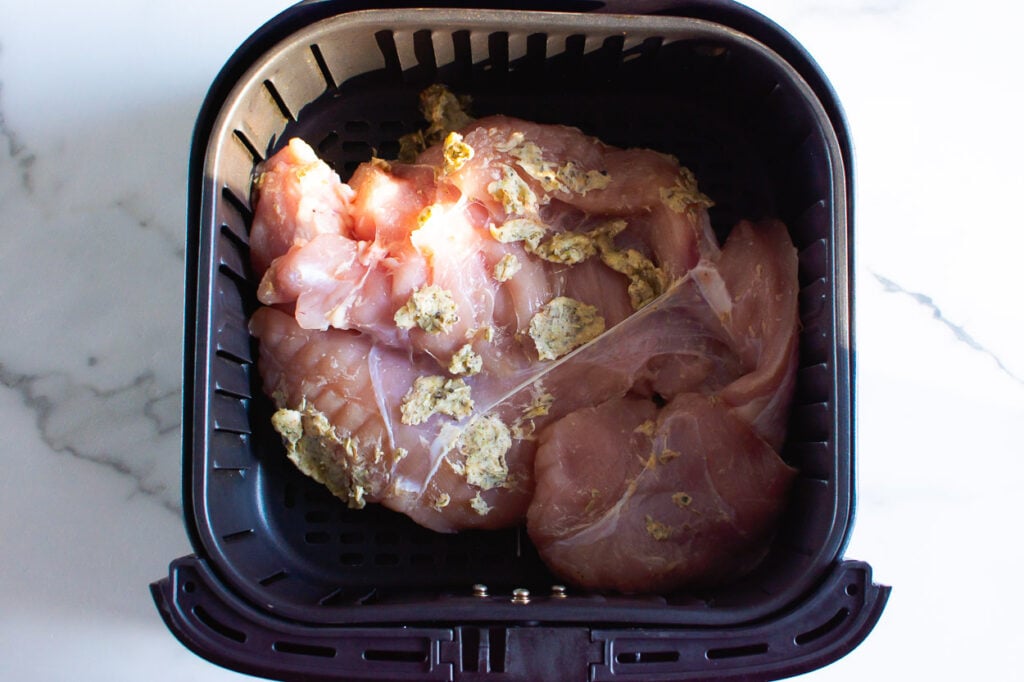 Raw turkey breast with herb butter placed in air fryer.