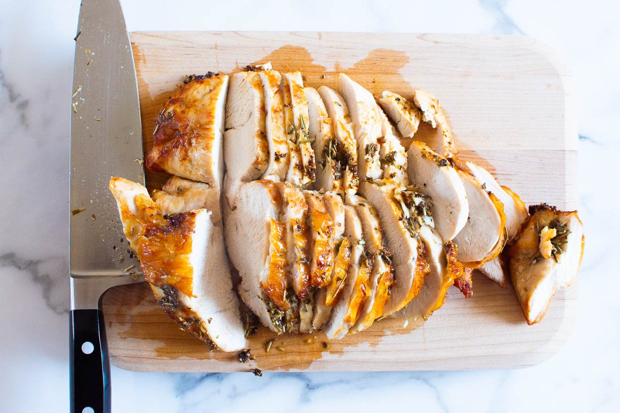 Turkey breast sliced on cutting board with knife.