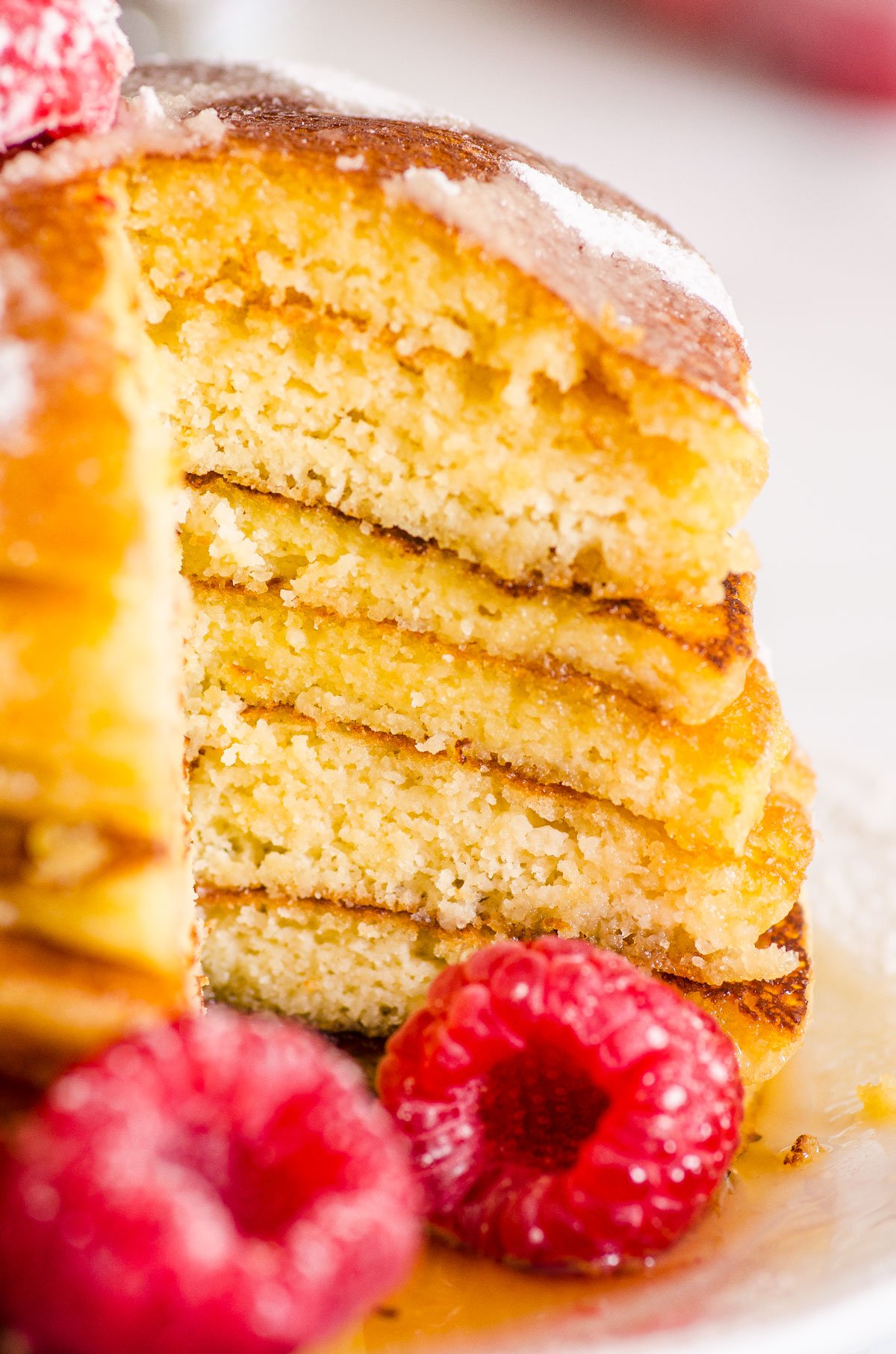 Stack of almond flour pancakes sliced into with fresh raspberries on a side.