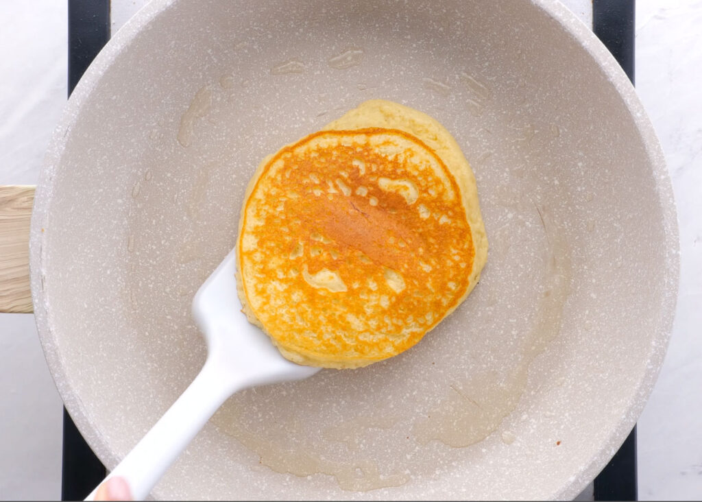almond flour pancakes being lifted out of skillet with spatula