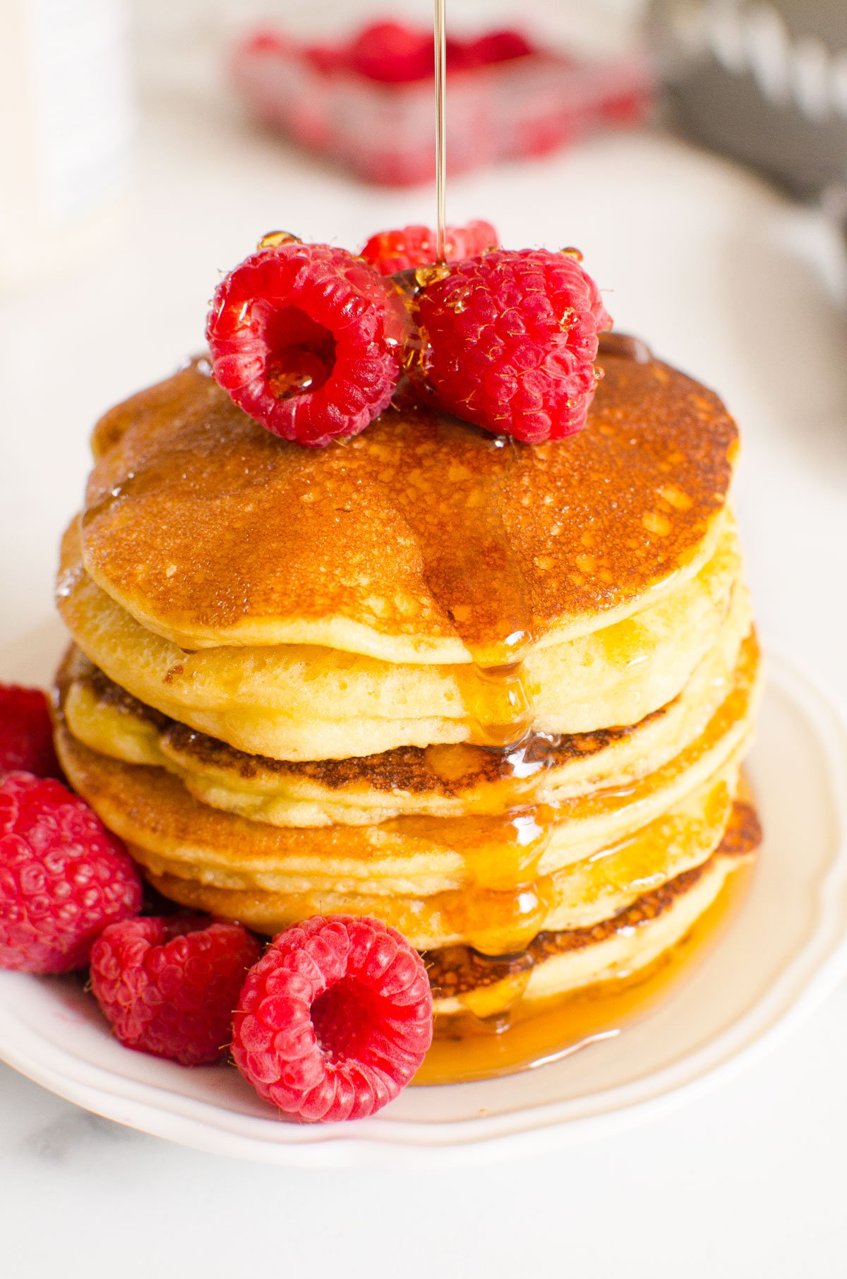 Almond flour pancakes with syrup and raspberries on a plate.