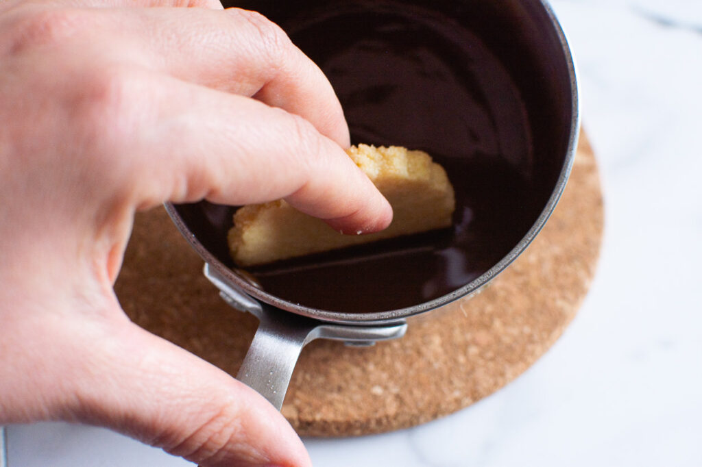 Dipping a shortbread cookie in melted chocolate.